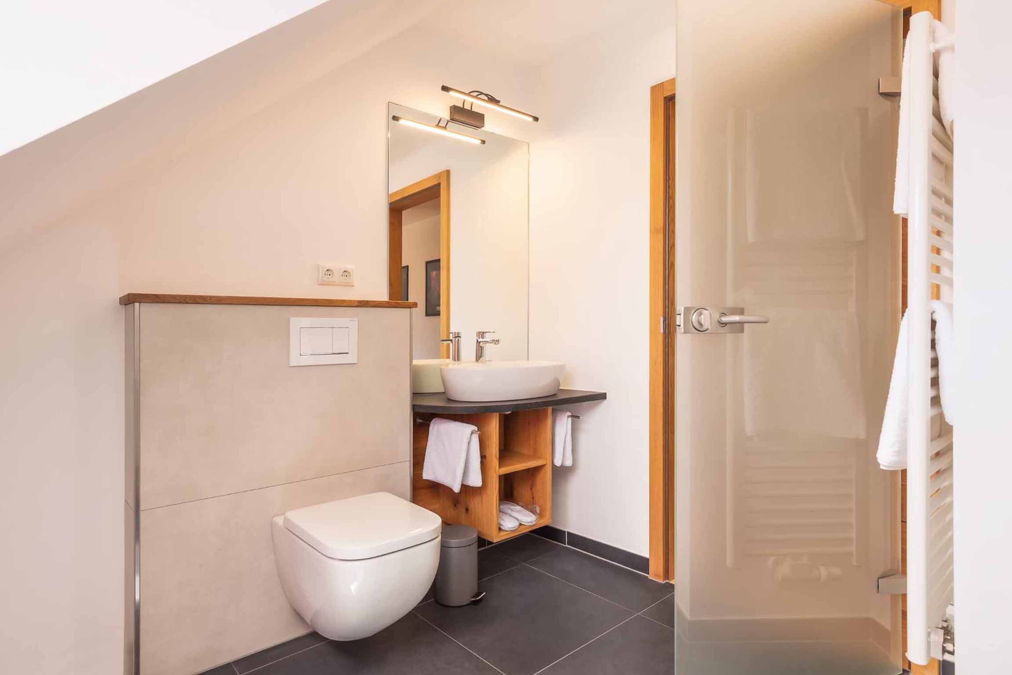 Un baño moderno con inodoro, lavabo y espejo.