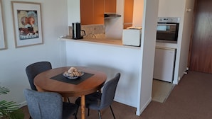 A compact kitchen with white cabinets, a coffee machine, and a built-in oven.