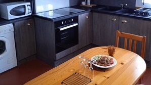 Une cuisine compacte dotée d’appareils électroménagers modernes, une table à manger en bois et une vue sur l’extérieur.
