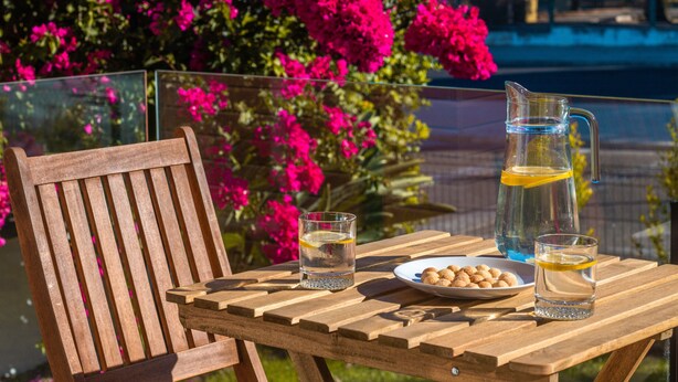 Une table en bois avec une carafe, des verres et une assiette de collations.