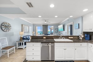 A modern kitchen with white cabinets, a dishwasher, and a large island with a sink.