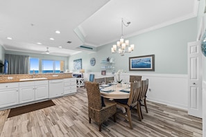 A modern kitchen with white cabinetry, a dining area with a round table, and a view to the outside.
