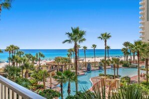 A resort with a pool, beach, and palm trees.