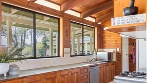 A modern kitchen with wooden cabinets, a dishwasher, and a stove. - Riverside Ranch - Oceanstays (Yamba)