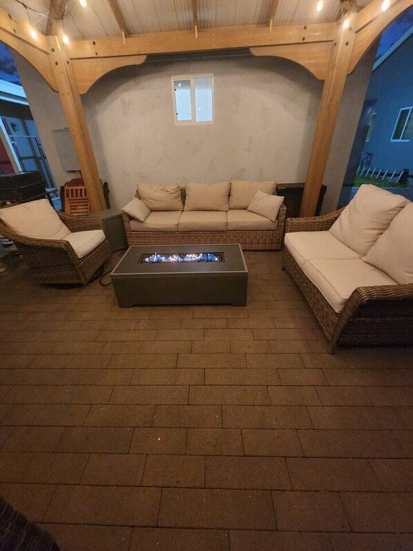 An outdoor seating area with wicker furniture, a fire pit, and a view of the surrounding buildings.