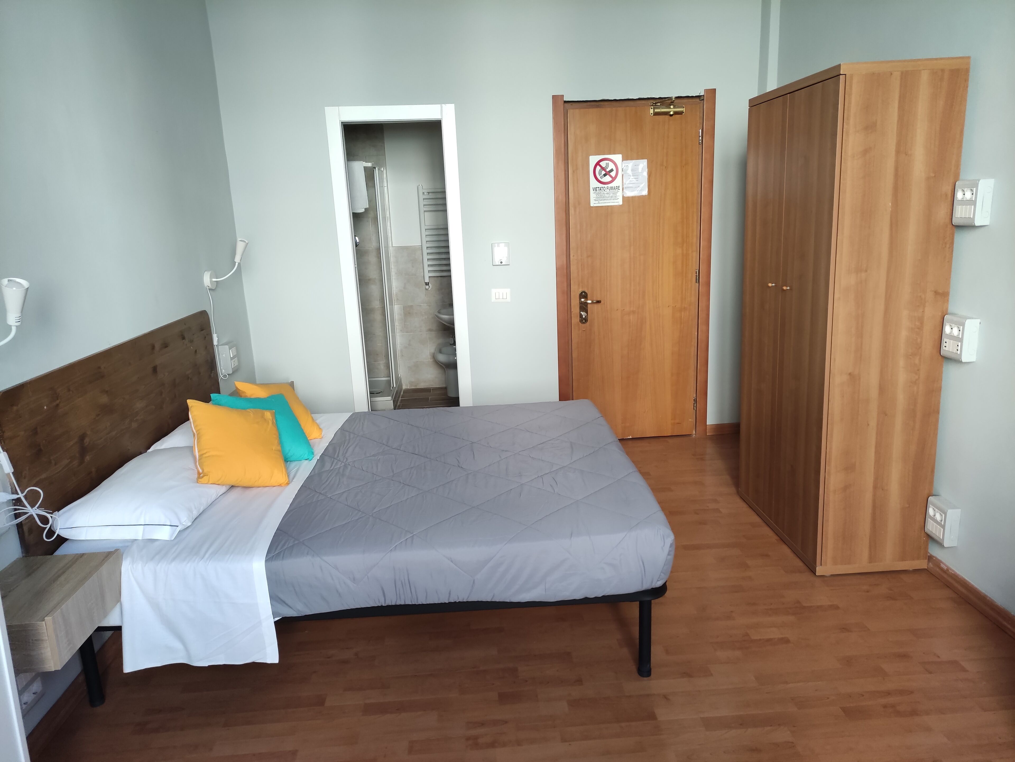 Une chambre à coucher comprenant un lit, une table de chevet, une armoire et une porte donnant sur une salle de bain.