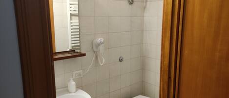 Un baño pequeño con lavamanos, bidé, inodoro y un secador de pelo montado en la pared.