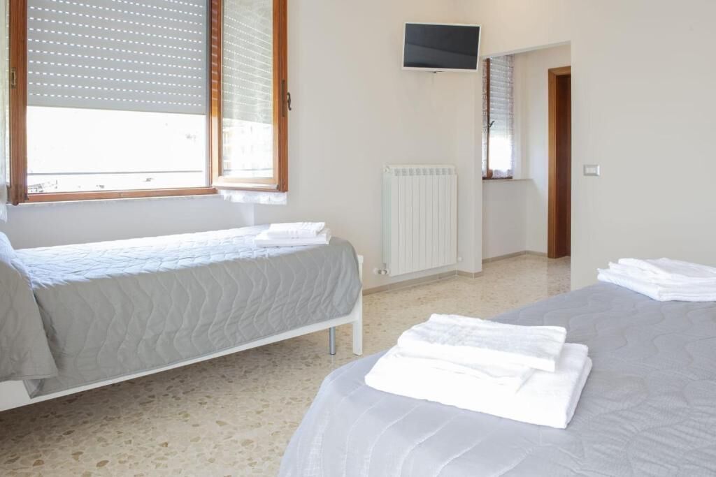Una camera da letto con due letti, una TV montata a parete e un termosifone.