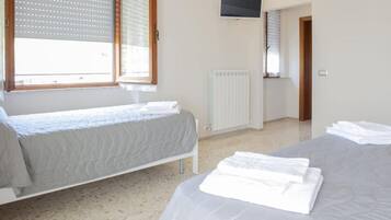 Una camera da letto con due letti, una TV montata a parete e un termosifone.
