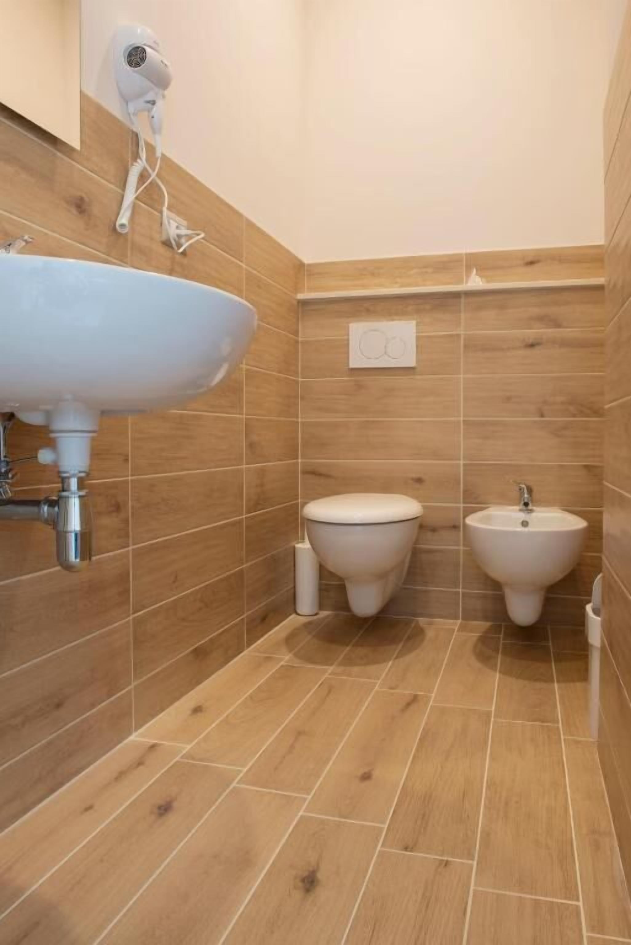 Ein Badezimmer mit einem Waschbecken, zwei Toiletten und einem Bidet.