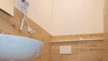 Ein Badezimmer mit einem Waschbecken, zwei Toiletten und einem Bidet.