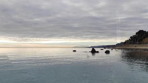 Une mer calme, parsemée de rochers, avec une côte lointaine.