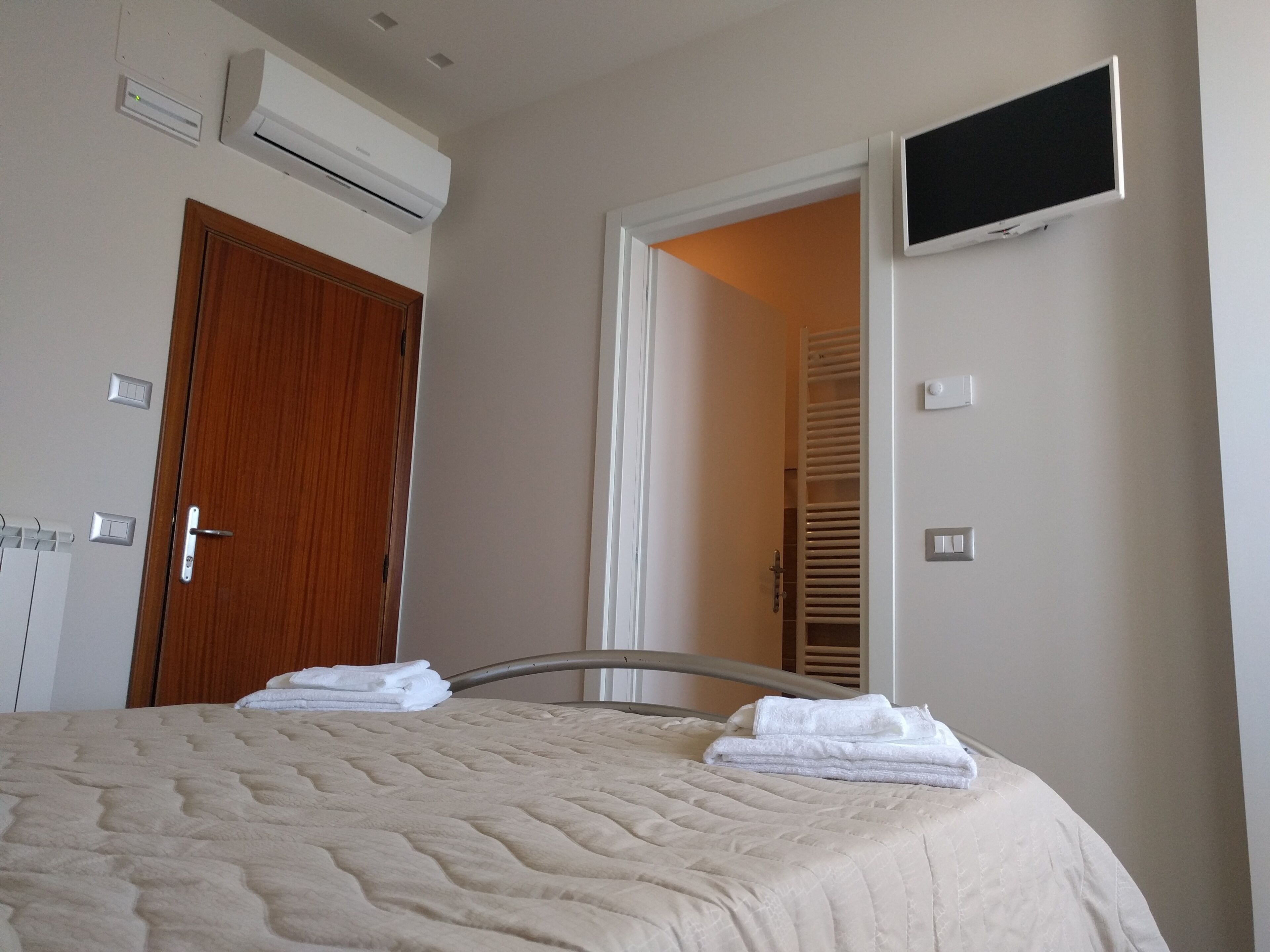 Una camera da letto con un letto, condizionatore, televisore e una porta che dà su un bagno.