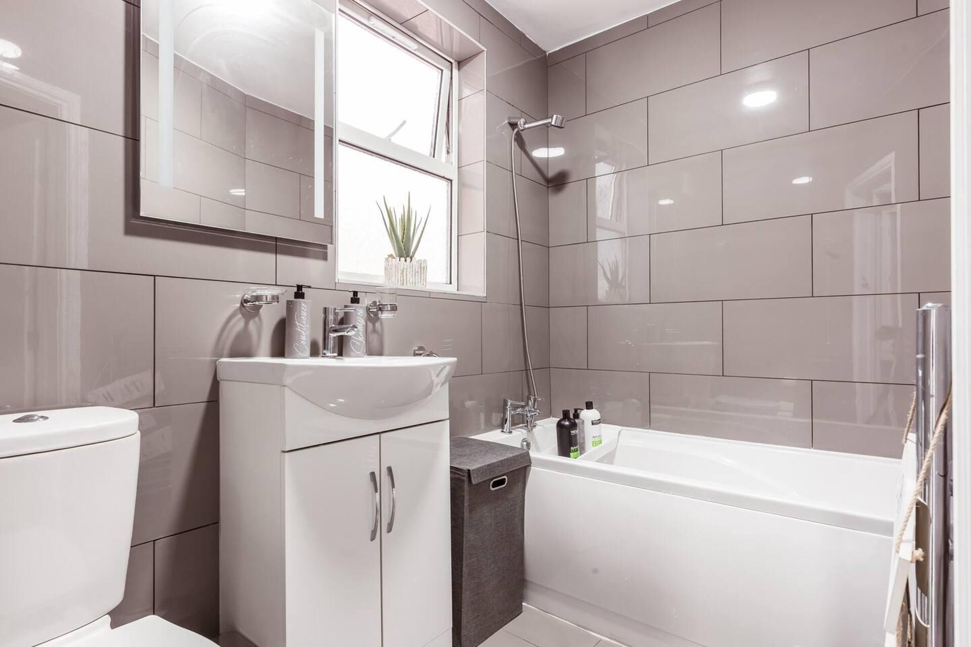 A modern bathroom with a toilet, sink, vanity, and bathtub.