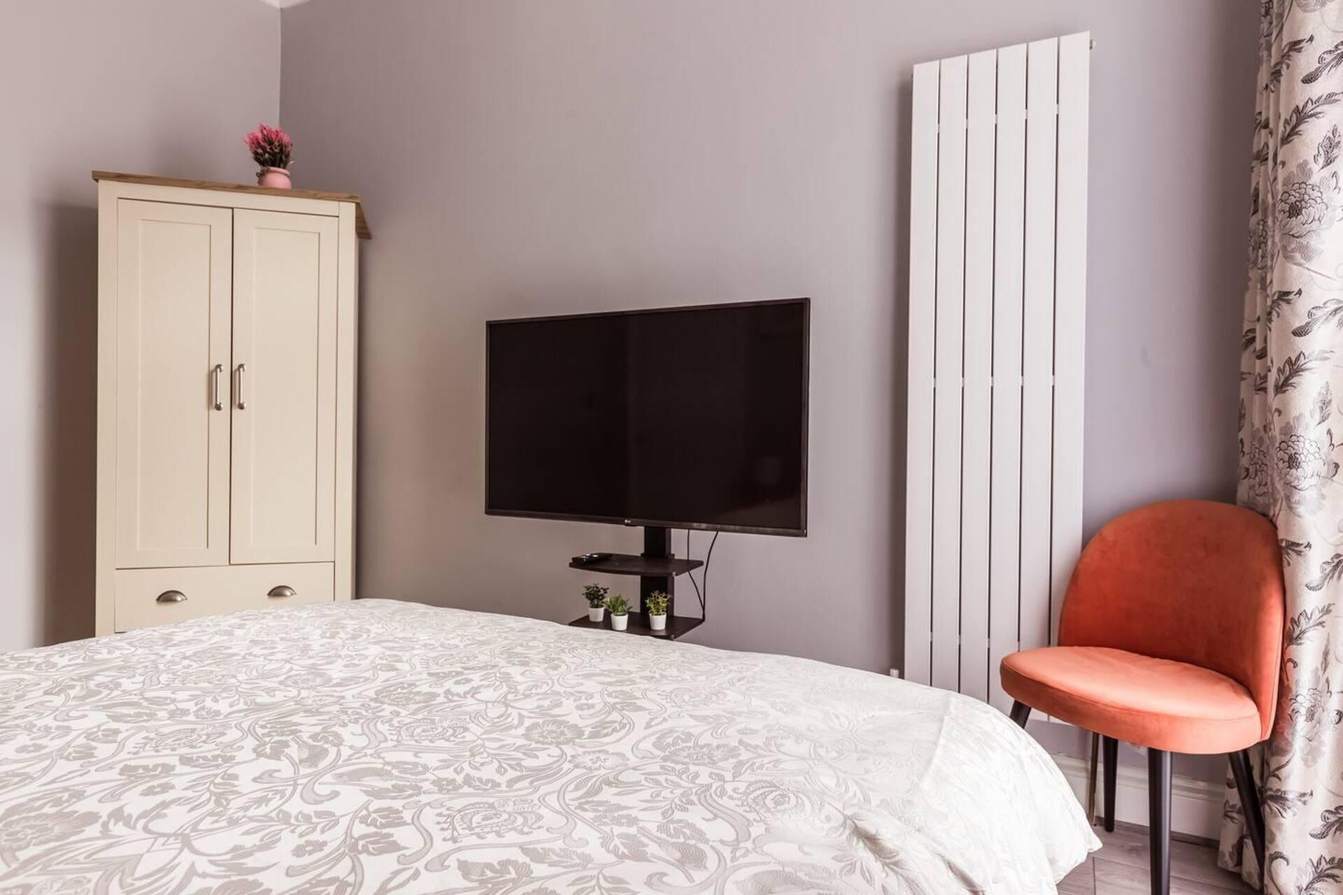 A bedroom with a bed, a television, a wardrobe, and a chair.