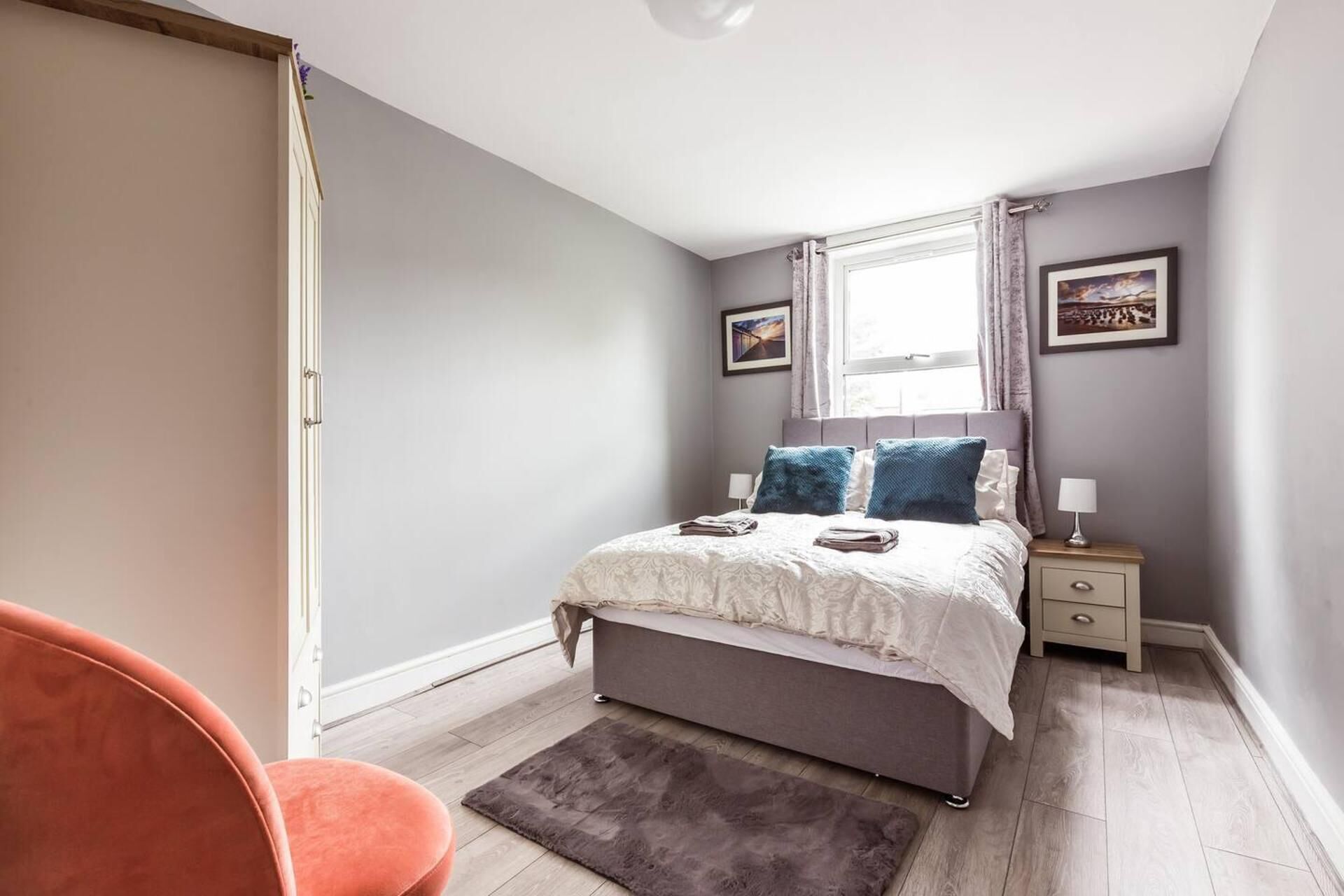 A bedroom with a bed, nightstands, a window with curtains, a rug, and a chair.