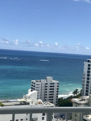 Um edifício alto com vista para o oceano e palmeiras.