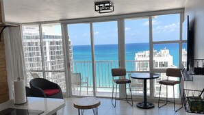 Een moderne hotelkamer met balkon, een kitchenette en uitzicht op de oceaan.