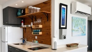 Een moderne keuken met een centraal eiland, donkere keukenkastjes en een houten accentmuur.