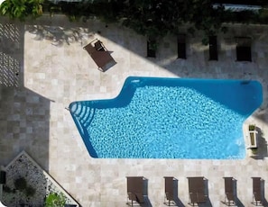 Vista aérea de uma piscina com espreguiçadeira e várias cadeiras de descanso.