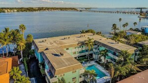 A hotel with a rooftop pool, surrounded by palm trees and a view of the sea. - Bay & Gulf Views. Waterfront+heated quiet pool+AC+2-minute walk to beach (Bradenton Beach)