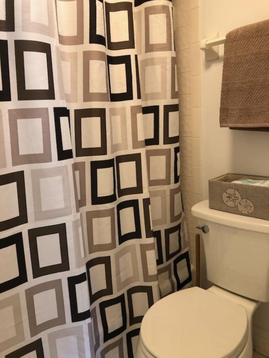 A bathroom with a patterned shower curtain, a toilet, and a towel rack.