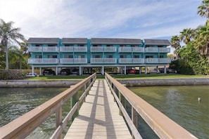 A two-story hotel with a pool and a wooden deck leading to it.