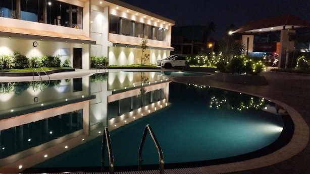 Un hôtel moderne doté d’une piscine, de nombreux balcons et d’espaces extérieurs bien éclairés.