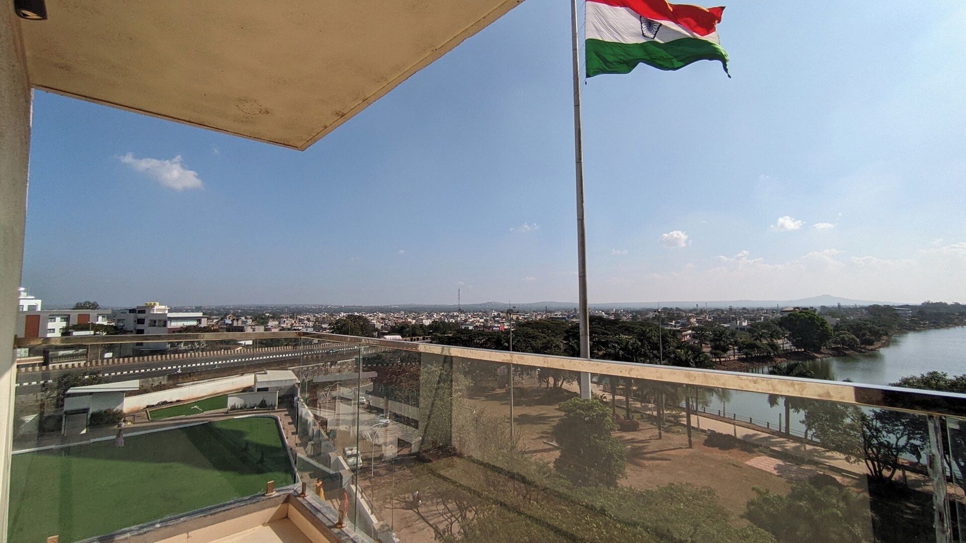 A balcony with a view of a cityscape, a flag, and a river.