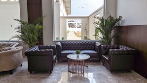 Un salon moderne avec un canapé d’angle, deux fauteuils et une petite table ronde.