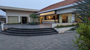 Un bâtiment moderne doté d’un toit plat, d’une grande entrée avec des marches et d’un espace jardin bien entretenu.