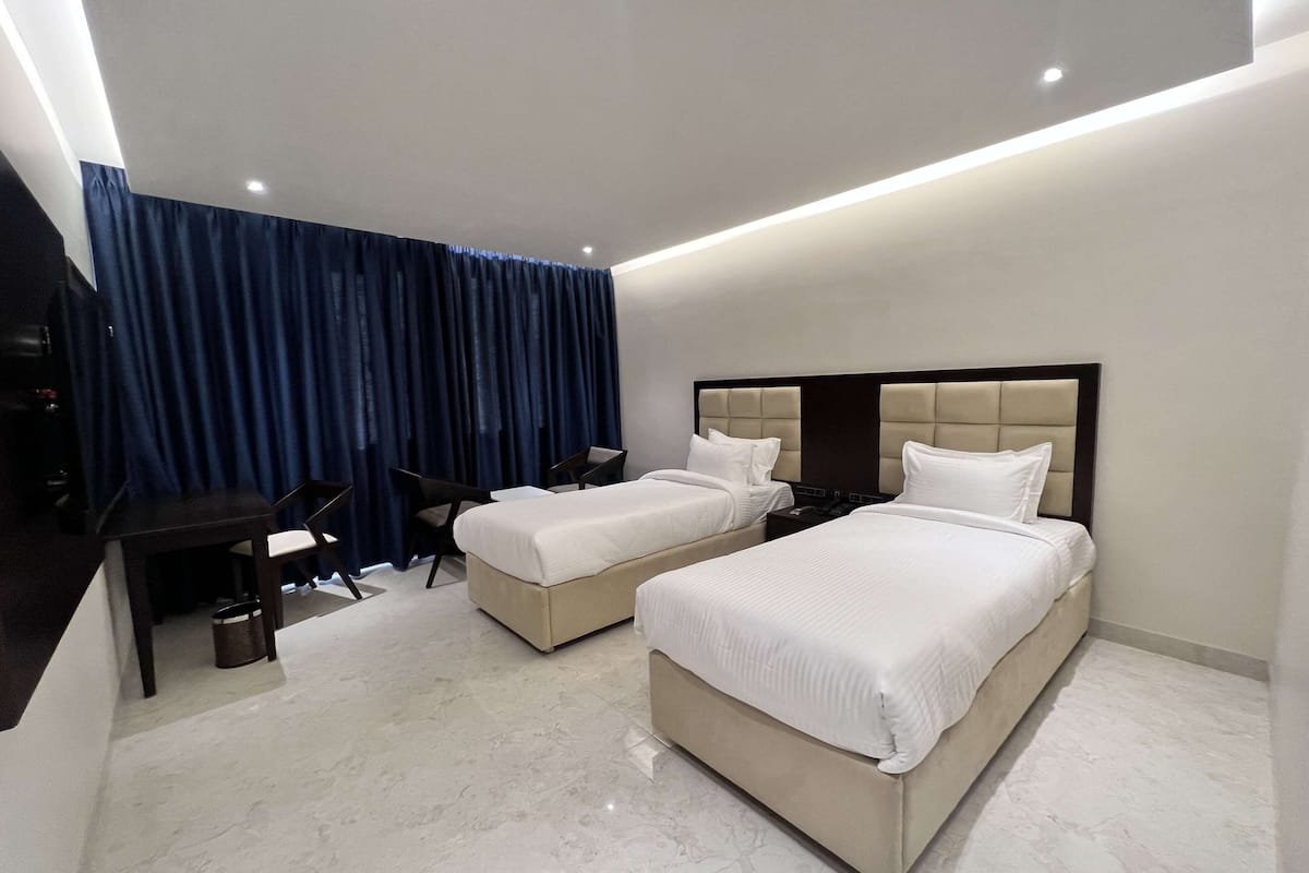 Ein Hotelzimmer mit zwei Betten, einem Schreibtisch und einem Stuhl.