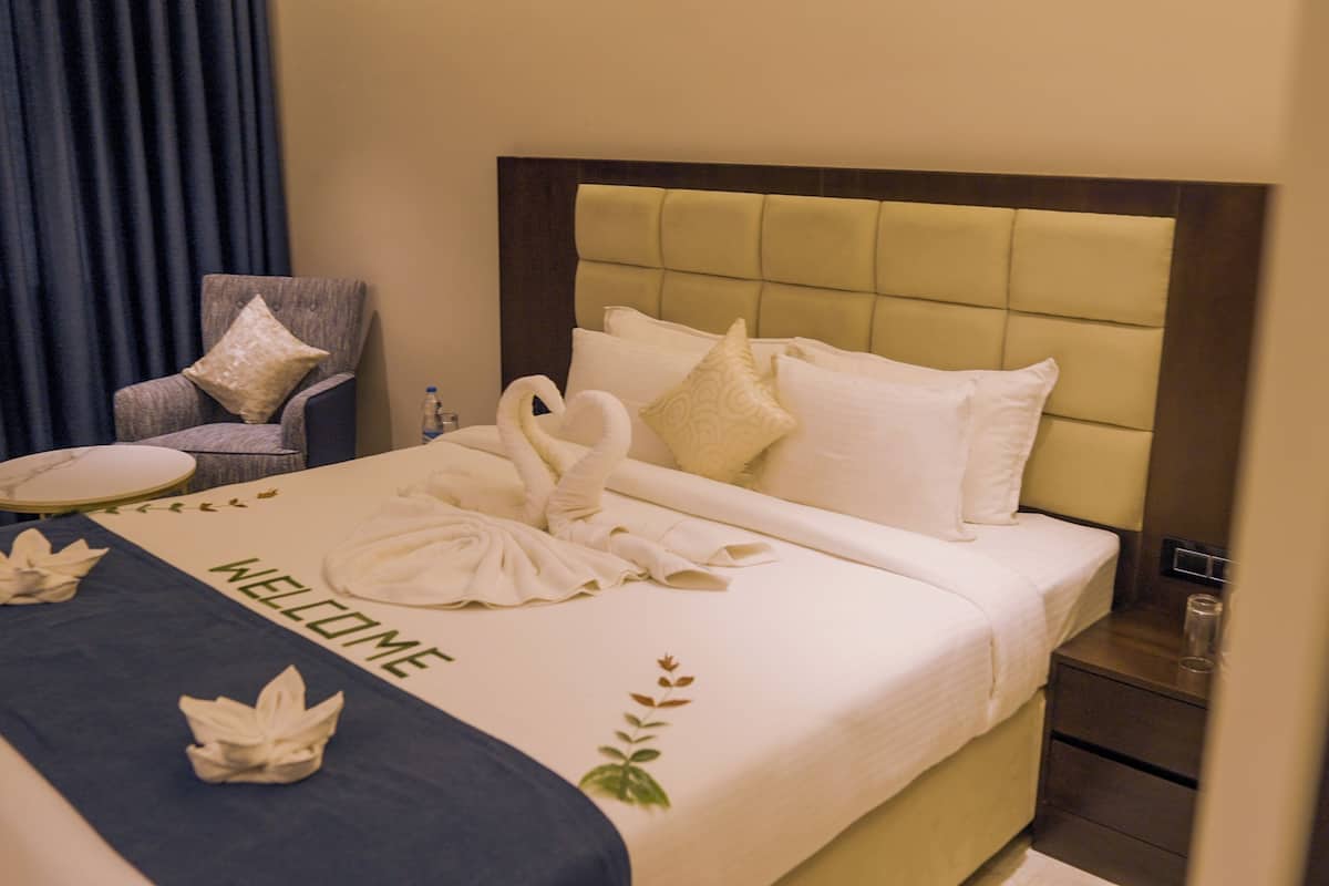 Ein Hotelzimmer mit Bett, Sessel, rundem Tisch und Nachttisch.