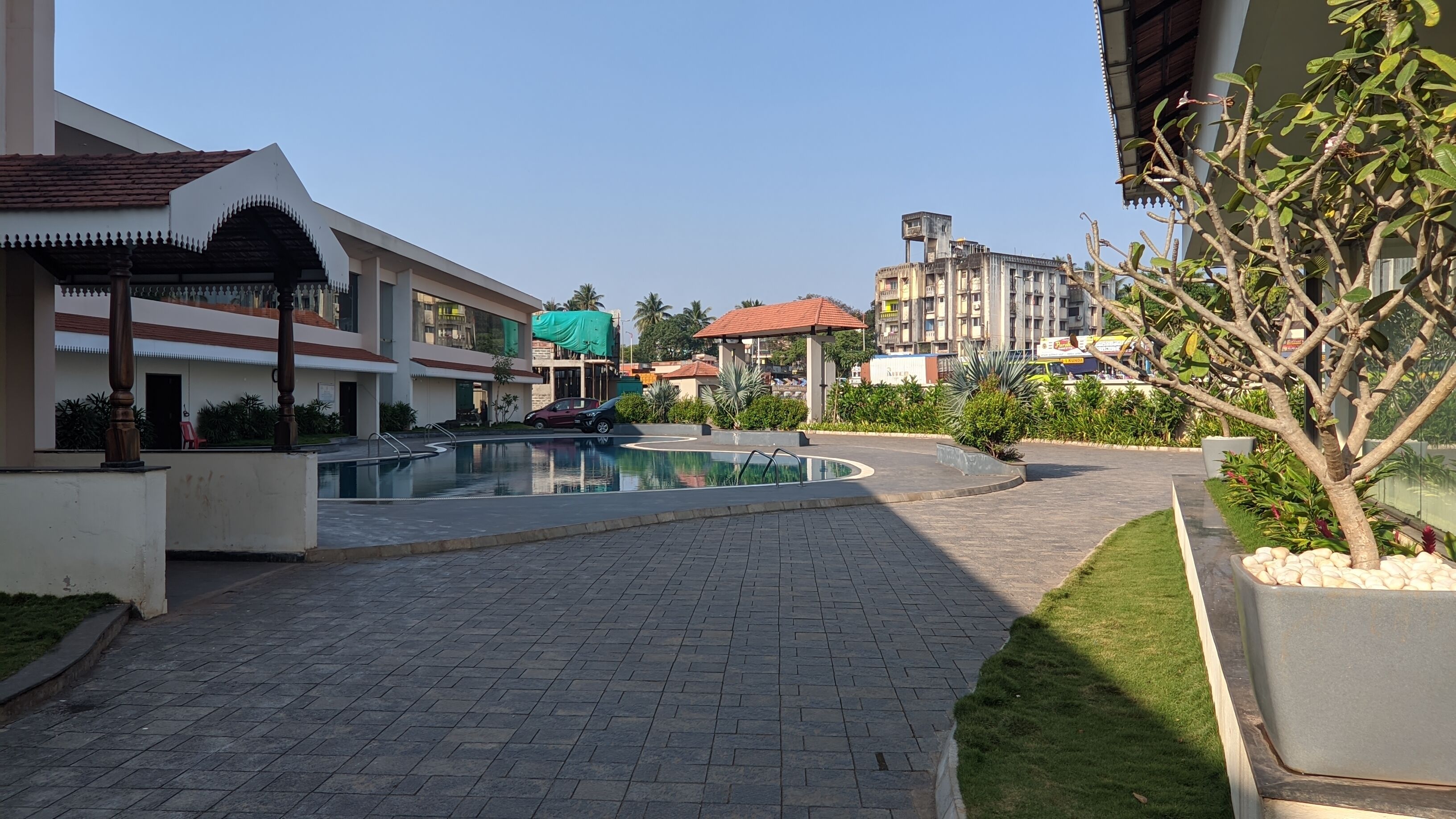 Un patio con piscina, senderos pavimentados y edificios circundantes.