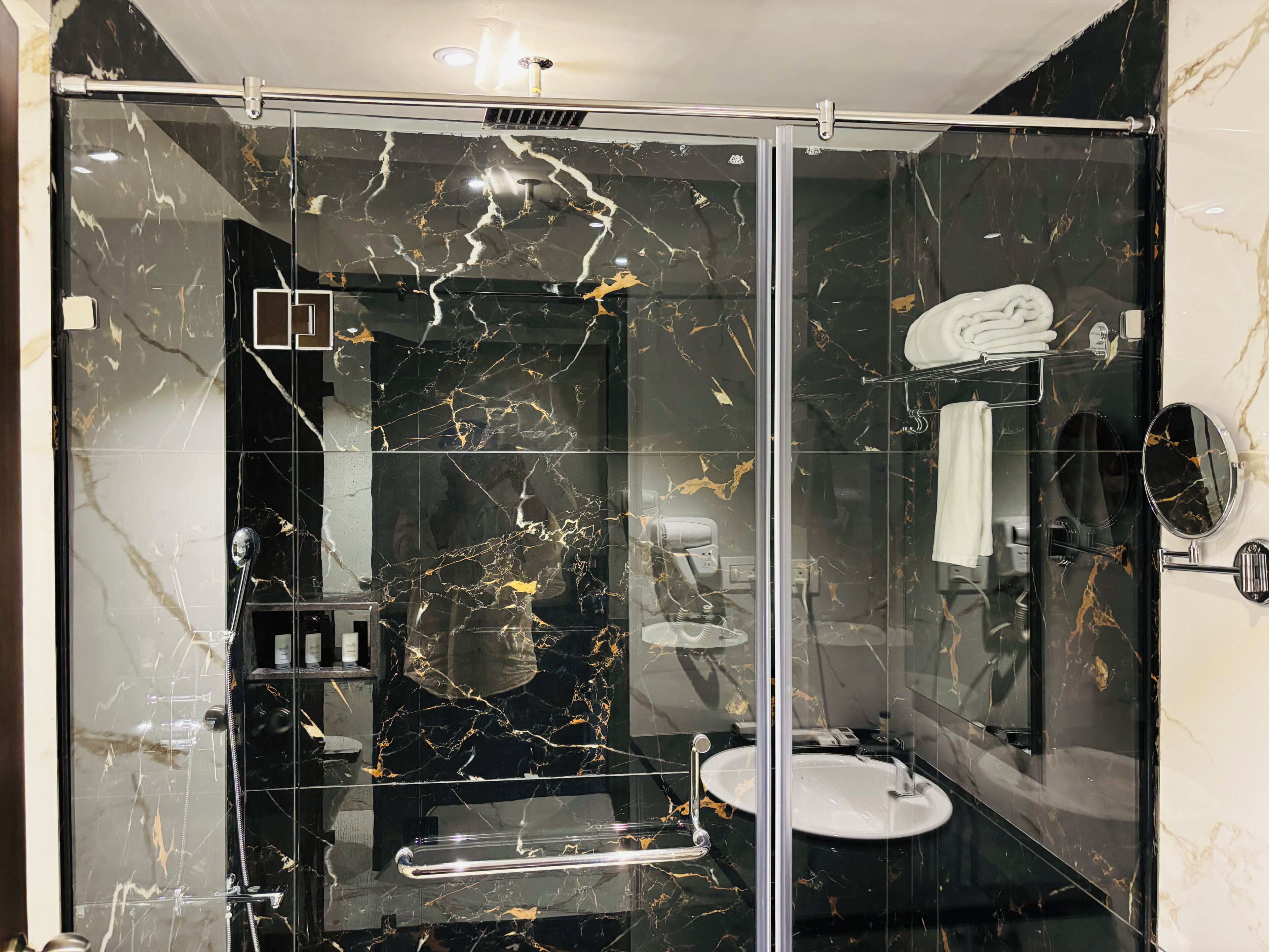A modern bathroom with a glass-enclosed shower, a white sink, and a mirror.