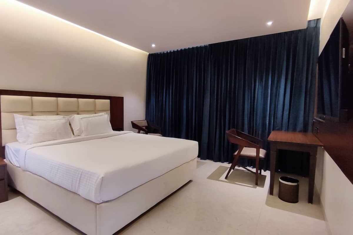 Ein modernes Hotelzimmer mit einem großen Bett, einem Schreibtisch, einem Stuhl und einem Fernseher.