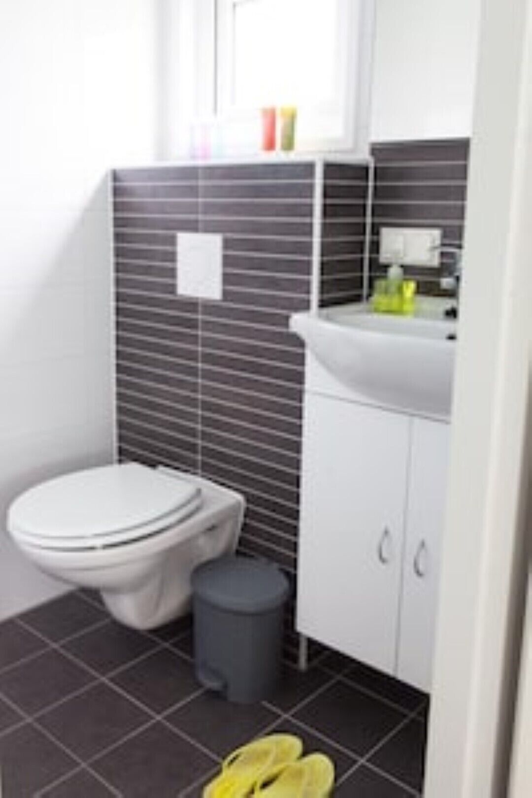 Une petite salle de bain avec des toilettes, un lavabo et une poubelle.