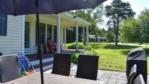 Une terrasse couverte avec une table et des chaises, un barbecue et un parasol.