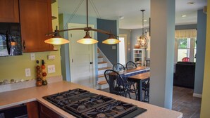 Une cuisine équipée d’une cuisinière à gaz, de meubles en bois et de luminaires suspendus.