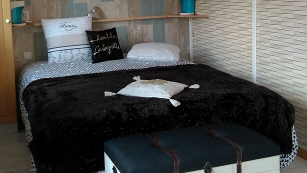A bedroom with a bed, bedside tables, a bench, and a wall with a textured pattern. - Baie de st valéry/somme le crotoy, cosy mobi-loft + hamman, sauna option (arrest)