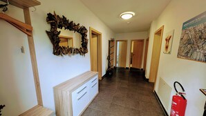 Um corredor com um banco de madeira, um espelho com moldura de madeira natural, um extintor de incêndio e um mapa na parede.