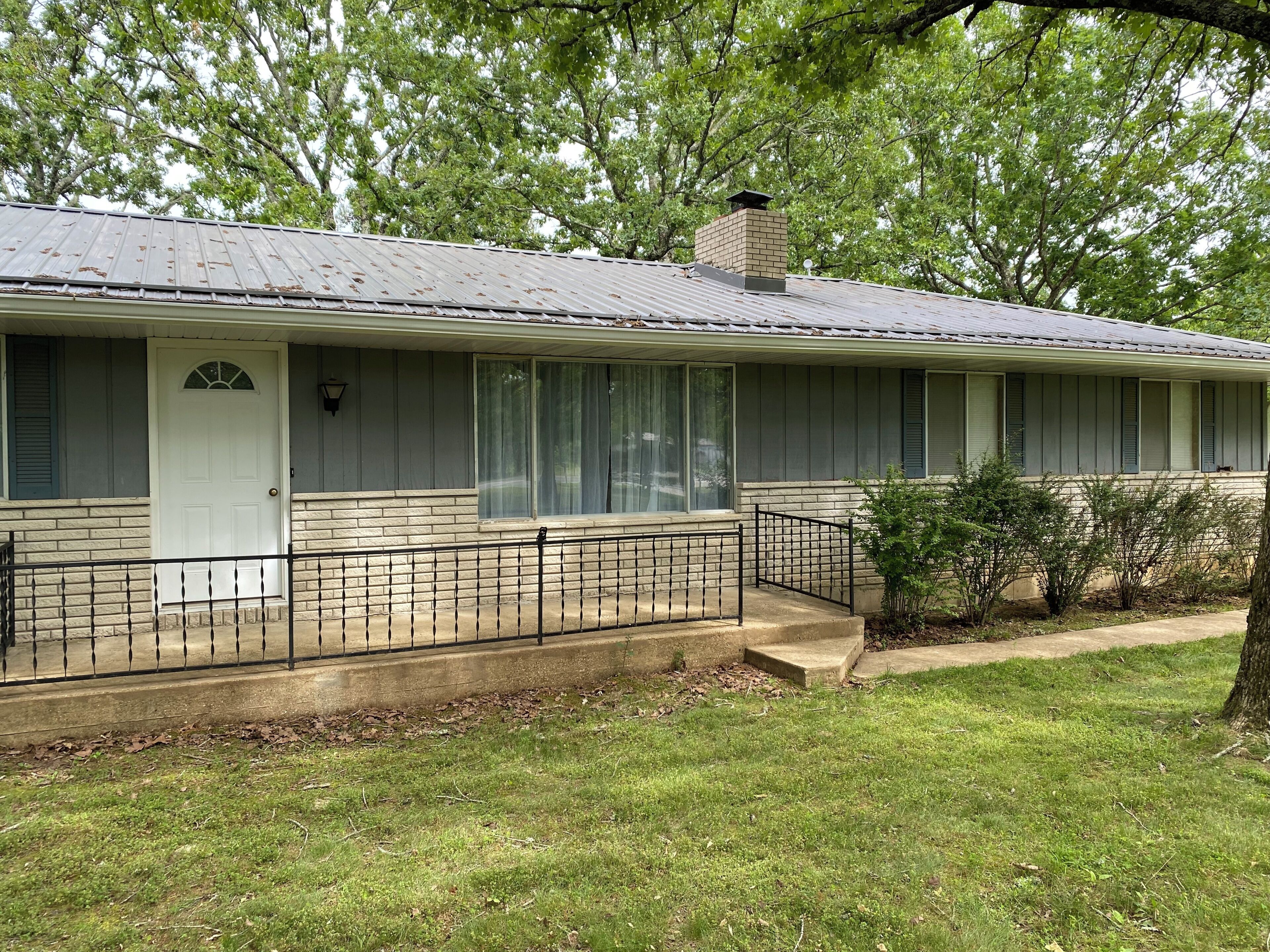 A single-story house with a front porch, a chimney, and a small front yard.