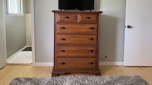 A wooden dresser with a television on top, positioned in a hallway with a door and a window.