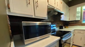 A kitchen with white cabinets, a stainless steel microwave, and a black oven.