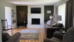 A living room with a fireplace, a sofa, a chair, and a television.