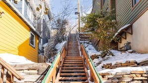 A wooden staircase leading up to a building with a yellow exterior wall.