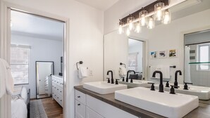 A modern bathroom with two sinks, a large mirror, and a wooden vanity.