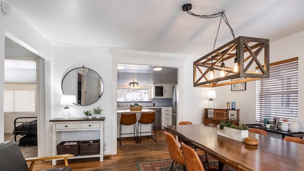 A modern kitchen with white cabinets, a round mirror, and a hanging light fixture.