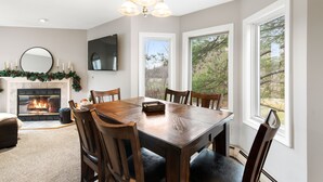 A dining room with a fireplace, large windows, and a chandelier. - Mount Snow Condo: 4 min Walk to Sundance Lift (High Speed - 6 Seat) (Dover)
