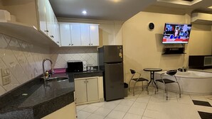 A modern kitchen with a built-in island, a refrigerator, a microwave, and a television mounted on the wall. - Freeway Pattay make you feel as home (Pattaya)